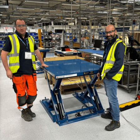 Salman and Tom install scissor lift tables in manufacturing plant.
